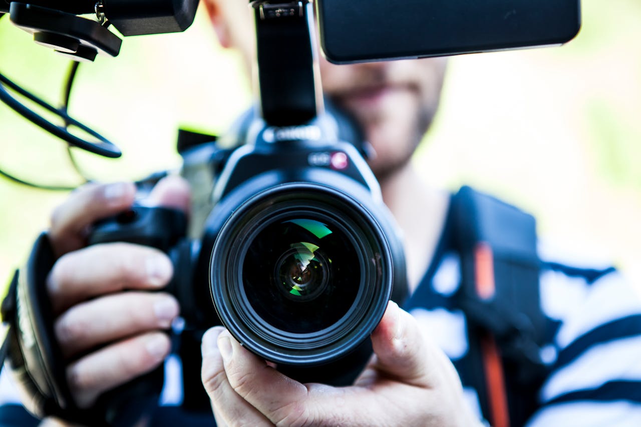 footer-01 A close-up shot of a cameraman filming, focusing on the camera lens and equipment.