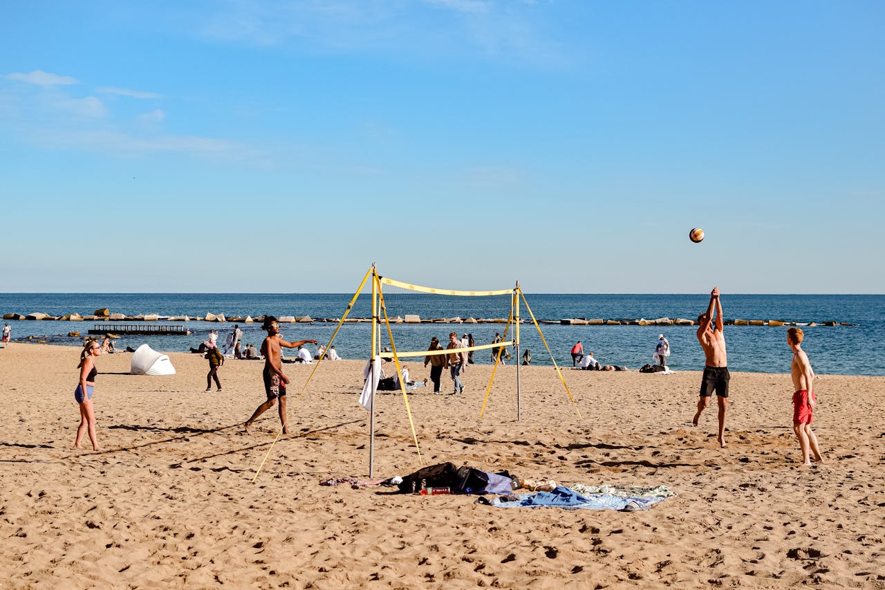 journey-img Energetic game of beach volleyball under clear skies by the seaside.