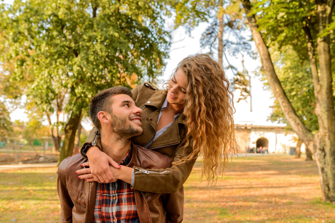 mission-img Smiling couple embracing in a sunlit park during fall, capturing love and joy.